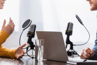 Radyo stüdyosunda muhabirle konuşurken el kol hareketi yapan kadın görüntüsü.
