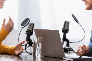 cropped view of woman gesturing while talking to interviewer in radio studio clipart