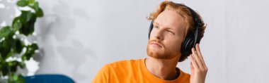 website header of thoughtful man looking away while listening podcast in wireless headphones clipart