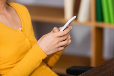 Evde akıllı telefondan sohbet eden genç bir kadın görüntüsü, seçici bir odaklanma.