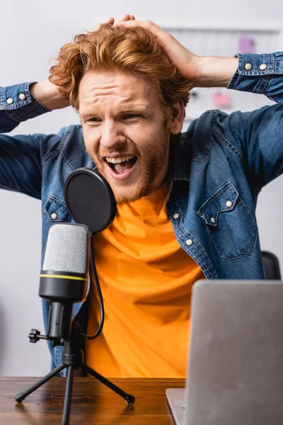職場でマイクで叫んでいる間に頭に触れる怒りのアナウンサー — ストック写真