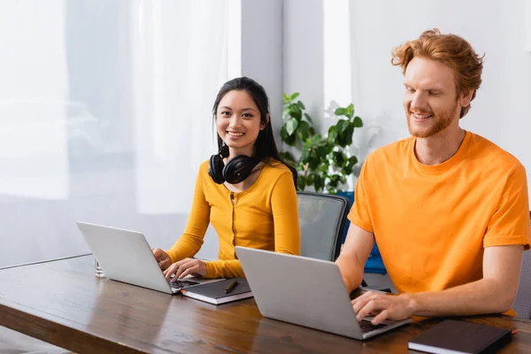 Morena Asiático Freelancer Con Auriculares Inalámbricos Cuello Mirando Cámara Mientras — Foto de Stock