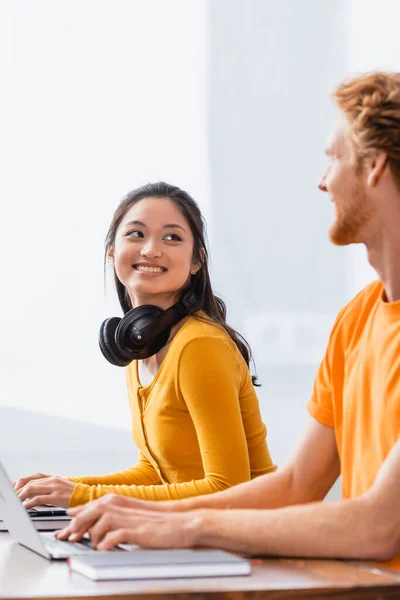 Excited Asian Freelancer Wireless Headphones Neck Looking Young Man While — Stock Photo, Image