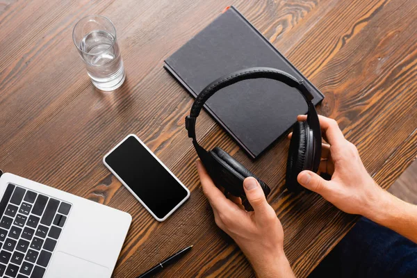 Cropped View Freelancer Holding Wireless Headphones Smartphone Blank Screen Laptop — Stock Photo, Image