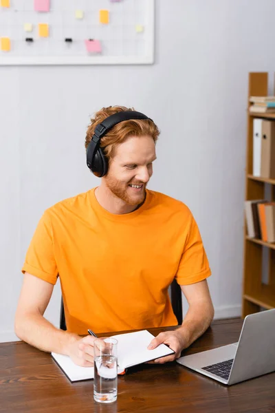 Young Freelancer Wireless Headphones Writing Notebook While Looking Laptop — Stock Photo, Image