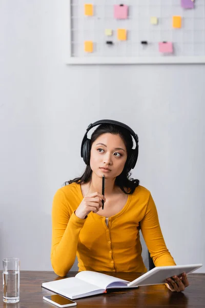 Thoughtful Asian Student Wireless Headphones Holding Digital Tablet Pen Empty — Stock Photo, Image