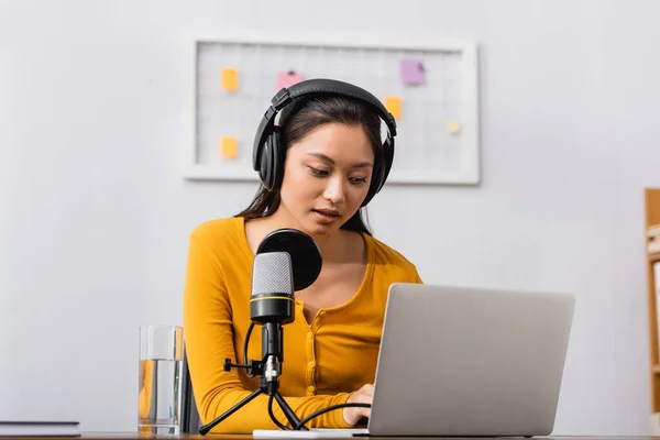 Koncentrerad Asiatisk Radio Värd Trådlösa Hörlurar Med Hjälp Laptop Nära — Stockfoto