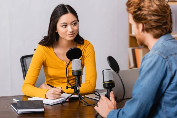 Selective Focus Young Asian Broadcaster Writing Notebook While Interviewing Man — Stock Photo, Image