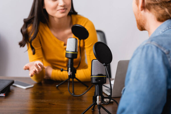 cropped view of radio host gesturing while interviewing man in studio