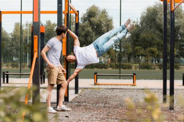 Genç çocuğun seçici odağı yatay çizgiler üzerinde egzersiz yapan sportif babaya bakıyor 
