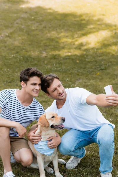 Pai Filho Adolescente Tomando Selfie Com Golden Retriever Parque — Fotografia de Stock