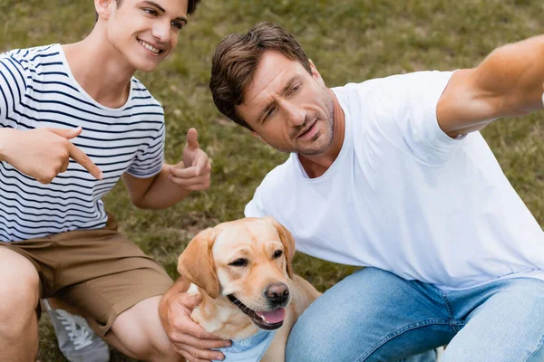 Adolescente Menino Apontando Com Dedos Golden Retriever Perto Pai — Fotografia de Stock