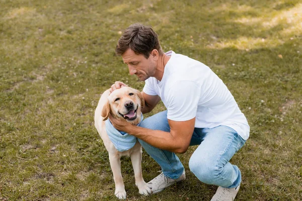 Hombre Jeans Vaqueros Camiseta Blanca Abrazando Golden Retriever Parque — Foto de Stock