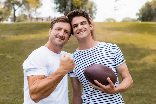 Stolzer Vater Zeigt Geballte Faust Und Steht Mit Rugbyball Neben — Stockfoto