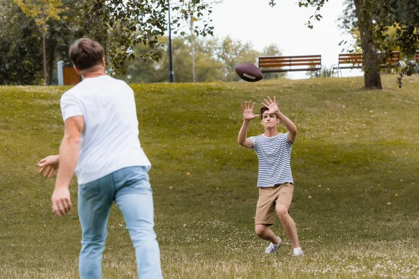 Селективное Внимание Подростка Ловившего Мяч Регби Рядом Отцом Парке — стоковое фото