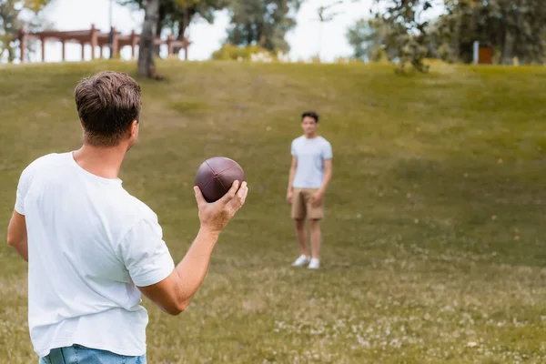 Selektivní Zaměření Otce Drží Rugby Míč Blízkosti Teenager Syn Zeleném — Stock fotografie