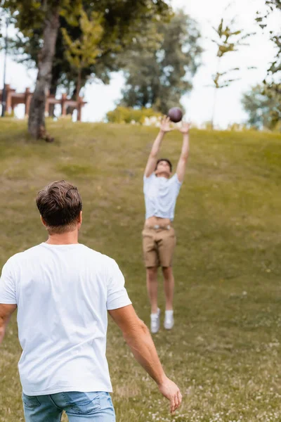 Baksida Bild Far Tittar Tonåring Son Fånga Rugby Boll Parken — Stockfoto