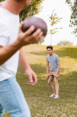 Gençlerin seçici odak noktası elinde rugby topu tutan babaya bakmak. 