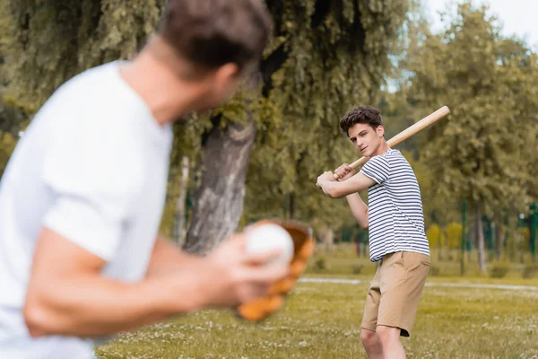 青少年男孩拿着垒球棒在公园里和男人打棒球的选择性焦点 — 图库照片