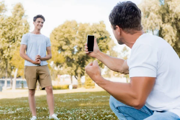 Selective Focus Man Holding Smartphone Taking Photo Teenager Son Park — Stock Photo, Image