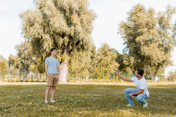 Vater Fotografiert Fröhlichen Sohn Mit Händen Taschen Grünen Park — Stockfoto