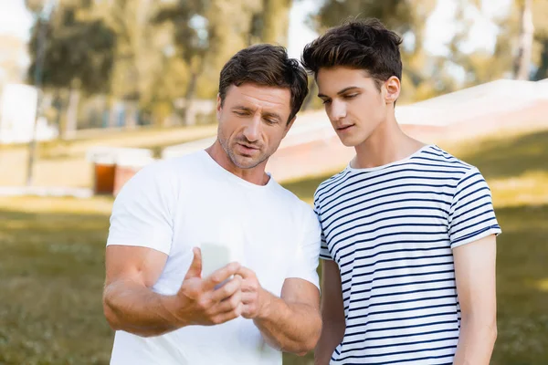 Man Using Smartphone Teenager Son Park — Stock Photo, Image