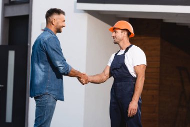 Binanın yakınında üniformalı bir adamla tokalaşan bir adam. 