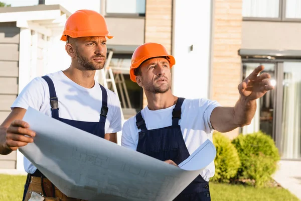 Budowniczy Wskazując Ręką Pobliżu Kolegi Planu Zewnątrz — Zdjęcie stockowe