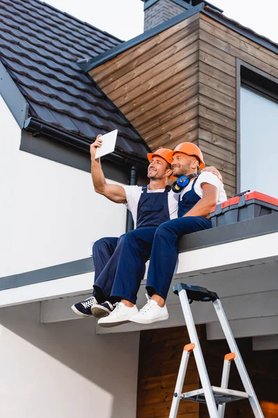 Budowniczowie Robiący Selfie Tablecie Cyfrowym Siedząc Dachu Budynku — Zdjęcie stockowe