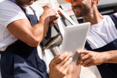 Kapıda merdivenin yanında dijital tablet kullanan işçilerin görüntüsü.