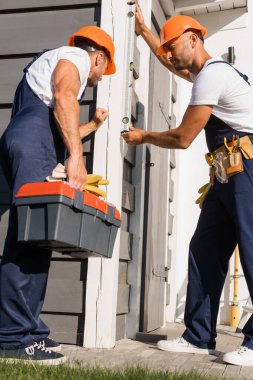 Aletleri ve ruhsal düzeyi olan işçilerin seçici odak noktası bina cephesi ile çalışıyor 