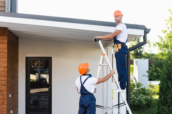 Handymen Hardhoeden Uniform Met Behulp Van Ladder Buurt Dak Van — Stockfoto