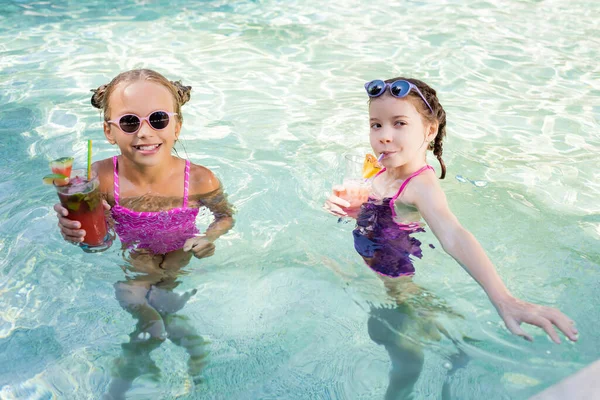 Chica Beber Cóctel Frutas Cerca Amigo Mientras Está Pie Piscina — Foto de Stock