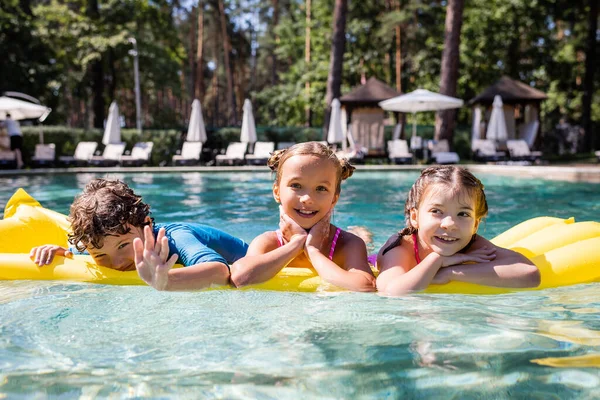 Joyful Boy Waving Hand Camera While Swimming Inflatable Mattress Girls — Stock Photo, Image