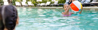 Yüzme havuzunda şişme top tutan bir kızın arka plan görüntüsü, panoramik konsept