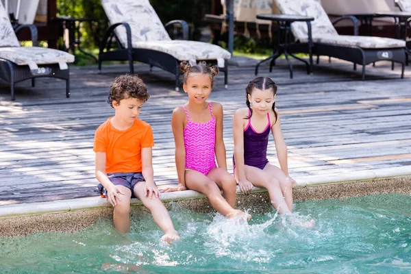 Girls Swimsuits Boy Shirt Sitting Poolside Making Water Splashes Legs — Stock Photo, Image
