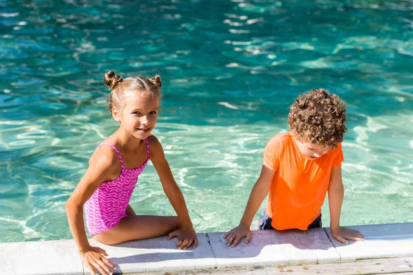 Chica Traje Baño Mirando Cámara Mientras Está Sentado Piscina Cerca — Foto de Stock