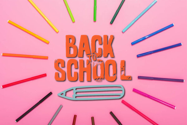 top view of frame of multicolored felt-tip pens and back to school on pink 