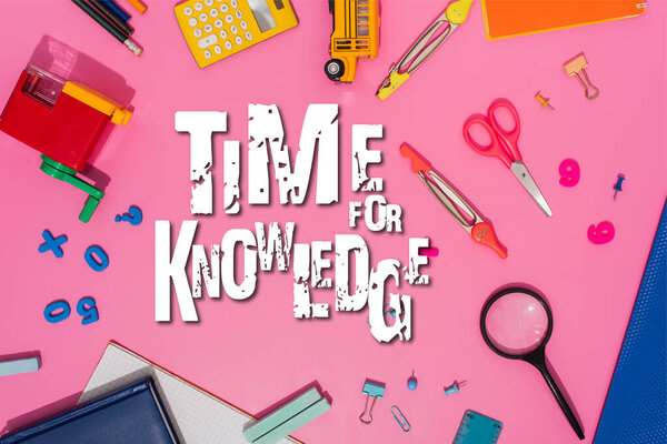 top view of stationery and toy school bus near time for knowledge lettering on pink 