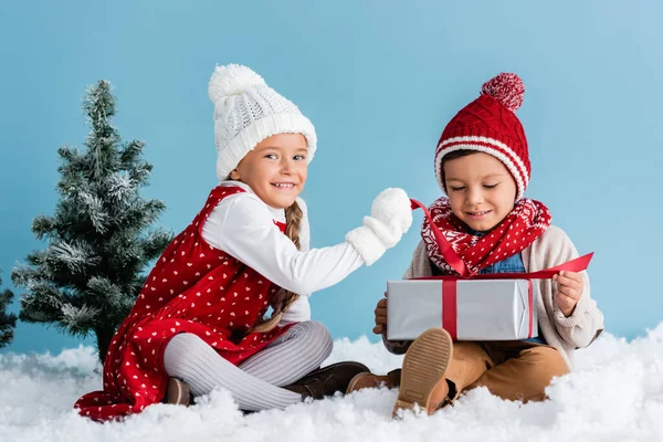 Niños Traje Invierno Sentado Nieve Tocando Caja Regalo Aislado Azul — Foto de Stock