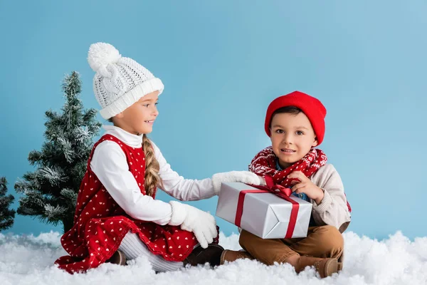 Kids Hats Winter Outfit Sitting Snow Touching Present Isolated Blue — Stock Photo, Image