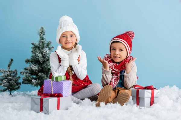 Niños Traje Invierno Sentados Nieve Haciendo Gestos Cerca Regalos Abeto — Foto de Stock