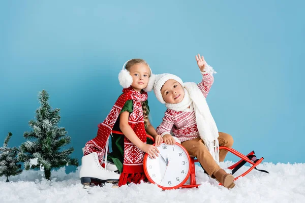 Kids Winter Outfit Sitting Sleigh Clock Pines Ice Skates Blue — Stock Photo, Image