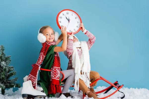 Kids Winter Outfit Sitting Sleigh Holding Clock Pine Ice Skates — Stock Photo, Image