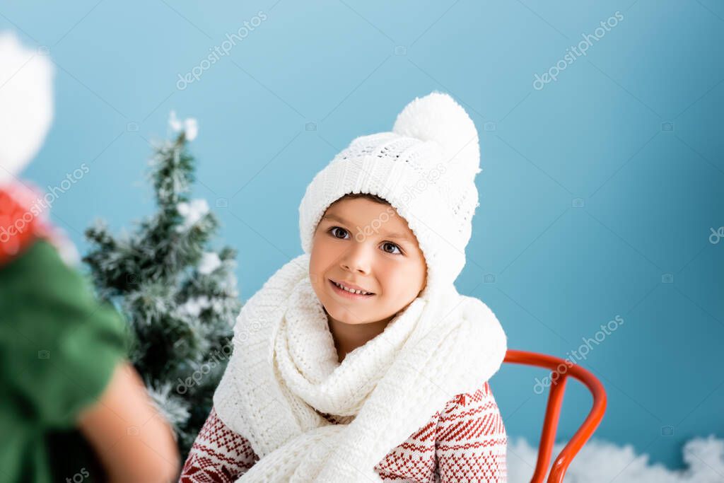 selective focus of boy in knitted scarf and hat on blue