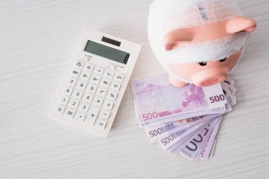 Hesap makinesinin yanındaki bantlı domuz kumbarasının en üst görüntüsü 