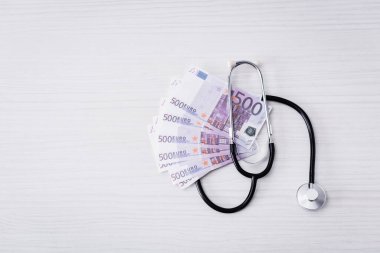 Beyaz masadaki steteskop ve avro banknotlarının en üst görünümü