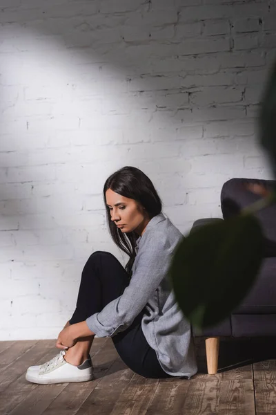 自宅のレンガの壁の近くの床に座っている悲しい孤独な女性精神衛生の概念 — ストック写真