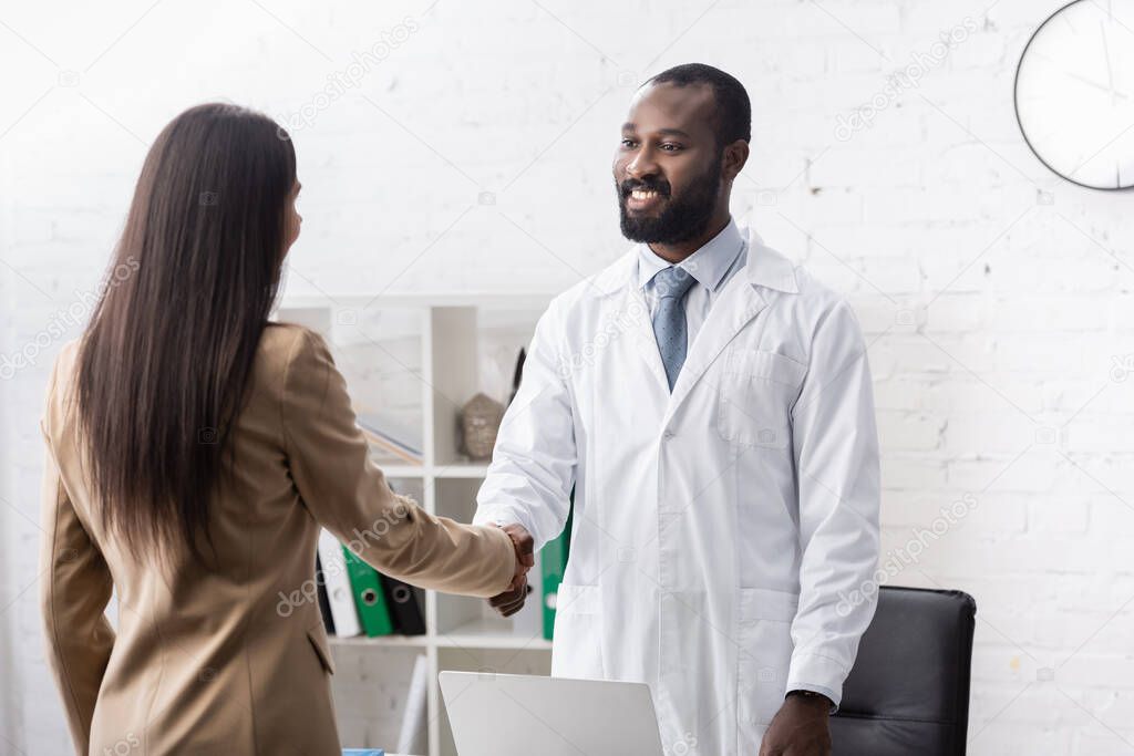African american doctor and patient shaking hands and looking at each other
