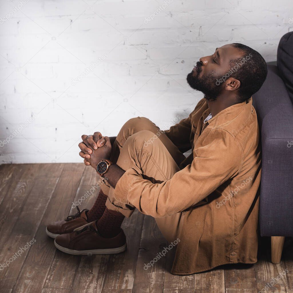 African american man sitting on floor with closed eyes